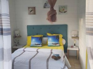 a bedroom with a bed with yellow and blue pillows at Bungalow chic à Sainte-Rose + piscine. in Sainte-Rose