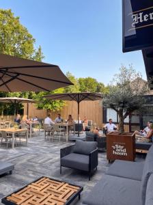 a patio with people sitting at tables and umbrellas at Vakantiepark 't Strandheem in Opende