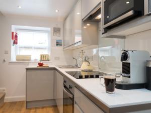a kitchen with white cabinets and a counter top at One Beckside Cottage in Staithes