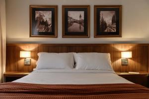 a bedroom with a bed with three pictures on the wall at Hotel Maerkli in Santo Ângelo +16 photos