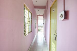 a hallway with pink and green walls and a white tile floor at Hotel O Suvidha in Jamshedpur