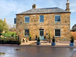a stone building with picnic tables in front of it at The Seagrave Arms in Weston Subedge