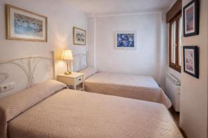 a bedroom with two beds and a lamp on a table at Apto Marita – Nueva de Llanes cerca de la Playa in Nueva de Llanes