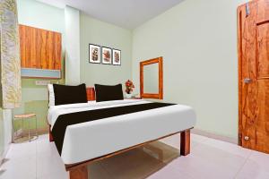 a bedroom with a white bed and a wooden door at Super Hotel O Dighori Nagpur in Sakardarā