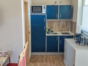a small kitchen with blue cabinets and a microwave at Holiday Home Goetheallee by Interhome in Krakow am See +10 photos