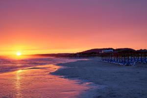 a sunset on a beach with chairs on the sand at SOL by Meliá Milanos Pingüinos in Son Bou