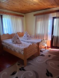 a bedroom with a bed with white sheets and windows at Cabana Codrii Apusenilor - Matis in Râșca