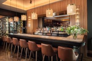 a bar in a restaurant with brown chairs at NH Lyon Airport in Saint-Exupéry