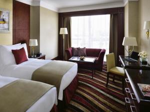 a hotel room with two beds and a chair at Mövenpick Hotel City Star Jeddah in Jeddah +128 photos