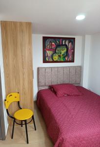 a bedroom with a bed and a yellow chair at Aparta estudio en Álamos in Pasto