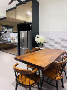 a kitchen with a wooden table with chairs and a refrigerator at Homestay Permai Inn in Temerloh