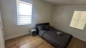 a bedroom with a bed and two windows at Comfortable Private Room Shared Bathroom in Vinita Park