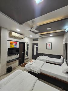 a bedroom with two beds and a flat screen tv at Hotel Royal Residency Executive in Miraj
