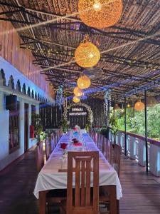 a long dining room with a long table with chairs and lights at Thisha Hotel & Restaurant in Jaffna
