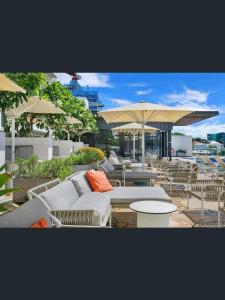 a patio with couches and tables and umbrellas at Bright CBD 2 bedroom resort-style escape in Brisbane