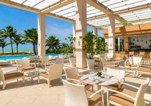 an outdoor patio with tables and chairs and a pool at Vila Gale Reserva do Paiva in Cabo de Santo Agostinho