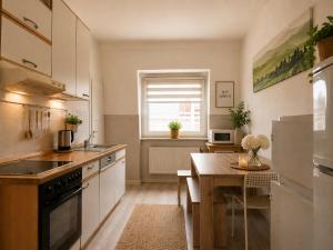 a kitchen with white cabinets and a wooden table at Apartments am Heimbach EG rechts in Kassel +6 photos