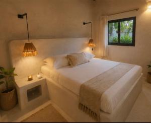 a bedroom with a large white bed with two lamps at Les Bungalows De Ja in Nosy Be