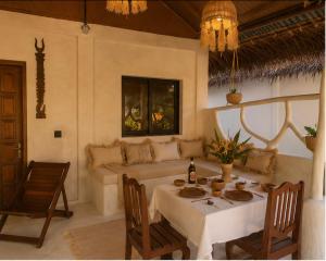 a dining room with a table and a couch at Les Bungalows De Ja in Nosy Be