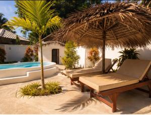 a patio with two chairs and an umbrella and a pool at Les Bungalows De Ja in Nosy Be +3 photos
