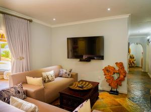 a living room with a couch and a tv on the wall at Kasimba Boutique Hotel in Gaborone