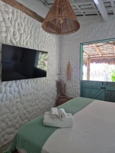a bedroom with two towels on a bed with a tv at Villa Água Viva in Itarema