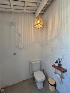 a white bathroom with a toilet and a light at Villa Água Viva in Itarema