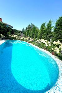 a large blue swimming pool in a yard with flowers at Эко отель Прованс Одесса in Odesa