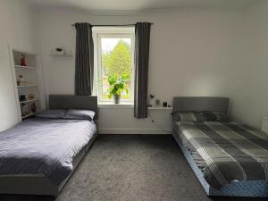 two beds in a room with a window at The M Rooms at 158 in Shotts Station
