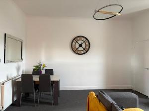a dining room with a table and a clock on the wall at The M Rooms at 158 in Shotts Station