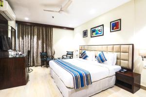 a hotel room with a bed and a flat screen tv at Bluestone Nehru Place by The Cosy Hotels in New Delhi