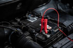 a red wire is plugged into the engine of a car at Corneille City in Kinshasa