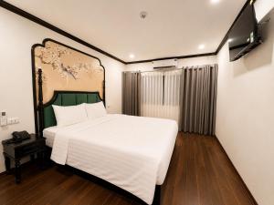 a bedroom with a large white bed and a flat screen tv at Hanoi Silk Crown Boutique Hotel & Spa in Hanoi