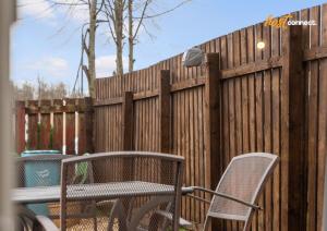 a wooden fence with two chairs and a trash can at 2Br House I Sleeps 4 I Cumbernauld in Cumbernauld