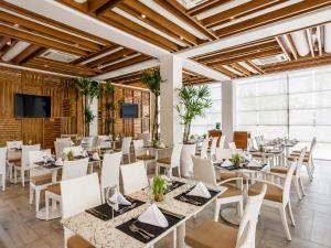 a restaurant with white tables and chairs and a flat screen tv at Vila Gale Reserva do Paiva in Cabo de Santo Agostinho