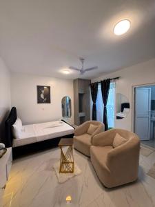 a bedroom with a bed and a couch and chairs at Coastal comfort studio apartment in Mombasa