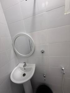 a white bathroom with a sink and a mirror at Coastal comfort studio apartment in Mombasa