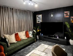 a living room with a green couch and a flat screen tv at The Peaceful Home in Nottingham