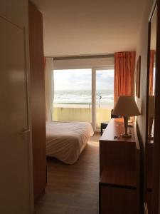a bedroom with a bed and a view of the beach at Hotel La Terrasse in Fort-Mahon-Plage