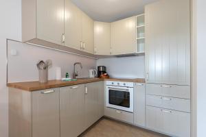 a white kitchen with white cabinets and a sink at Ferienwohnung "Ostseewind" - Bade- & Saunawelt täglich inklusive in Göhren