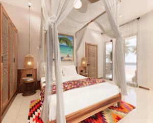 a bedroom with a canopy bed with a view of the ocean at Cocco Lagoon Resort & SPA 