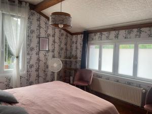 a bedroom with a bed and a chair and windows at Une nuit près de l'eau in Hallines
