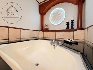 a bath tub in a bathroom with a clock on the wall at PD Full Seaview Water Chalet with Private Bathtub in Port Dickson +13 photos