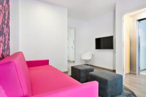 a living room with a pink couch and two stools at Mar Apartments in Barcelona