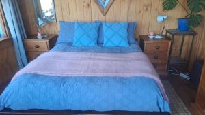 a bedroom with a blue bed with blue pillows at Delightful Dolphin 'Lodge' in Akaroa