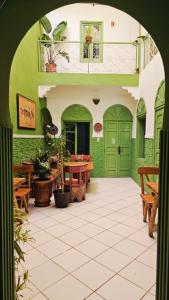 a patio with green doors and a table and benches at Dar Suncial in Marrakesh