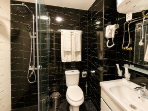 a black tiled bathroom with a toilet and a shower at Best One Hotel in Jizzax