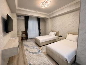 a hotel room with two beds and a television at Best One Hotel in Jizzax