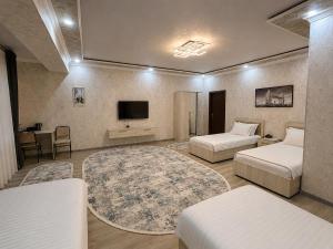 a hotel room with two beds and a tv at Best One Hotel in Jizzax