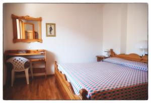 een slaapkamer met een bed, een bureau en een spiegel bij Casa Mizzau in Camporosso in Valcanale